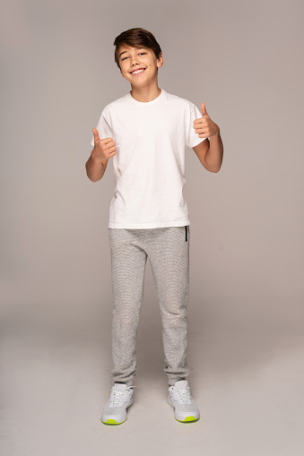 Full length photo of young handsome teenager man looking at the camera with smile and okay sign, isolated on white background