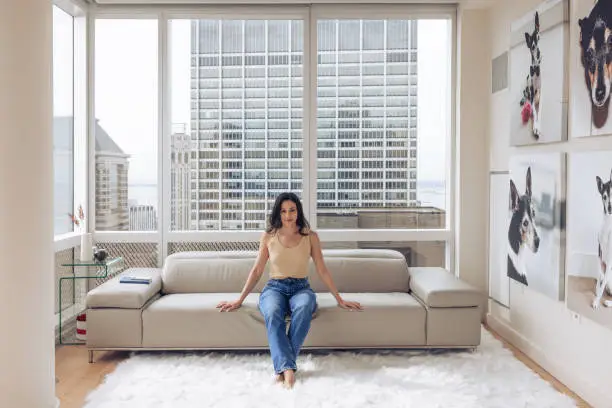 Photo of Woman sitting on the couch in her apartment and looking at camera