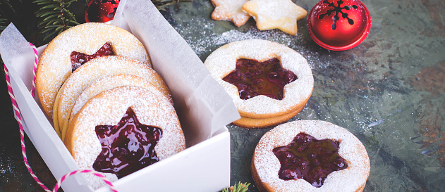 Christmas or New Year homemade sweet present in white box. Traditional Austrian christmas cookies - Linzer biscuits filled with red raspberry jam. Festive decoration.