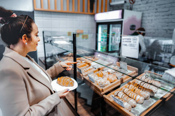 Woman choosing which freshly baked pastry to eat for breakfast
