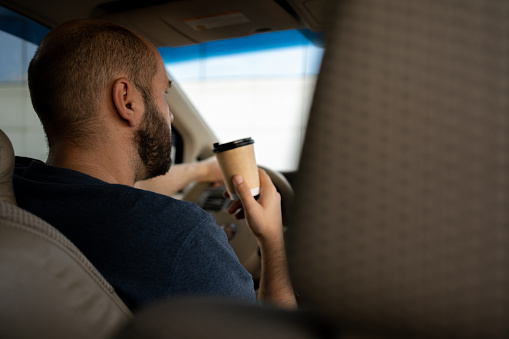 man drinking coffee while driving the car. transportation and vehicle concept