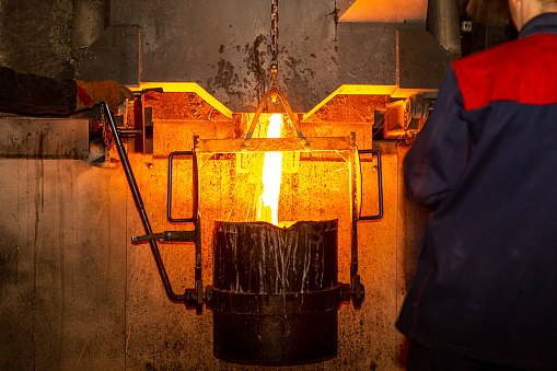 Pouring liquid metal from the furnace into the vat at metallurgical production. Metal part factory, foundry cast, heavy industry