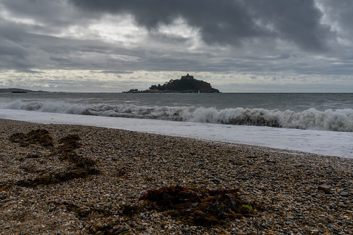 St. Michael's Mount, United Kingdom - 3 September, 2022: view of the St. Michael's Mount tidal island in Mount's Bay in Cornwall with waves crashing on a rocky beach