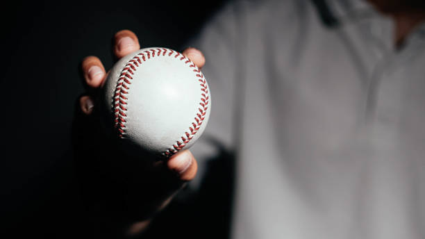 Selective focus of man holding baseball ball isolated on black background. Selective focus of man holding baseball ball isolated on black background. softball pitcher stock pictures, royalty-free photos & images