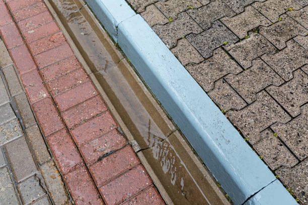 istock Rainwater runoff during rain. Concrete gutter for rainwater drainage between the sidewalk and the roadway. 1433418429
