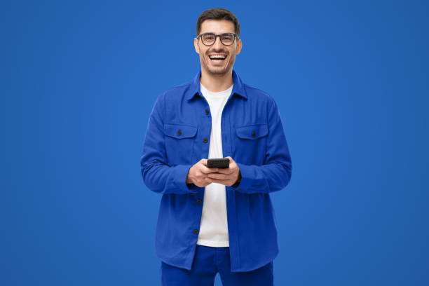 istock Young happy man laughing as he is looking at camera, holding his phone 1433419976