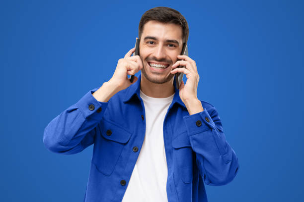 istock Busy businessman talking using two phones, isolated on blue 1433420012
