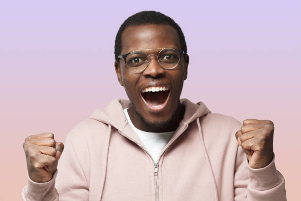 istock Young black male shouting while team win, raised both fist in victory gesture, isolated on purple 1433420977