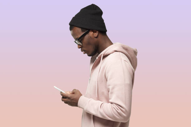 istock Young attractive black male looking at smartphone texting his friend, using mobile phone 1433421029