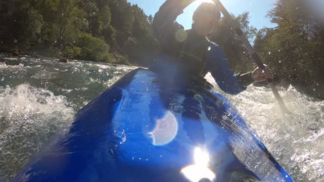Kayak deck, river waves, kayaker paddling over rapids, close up shot