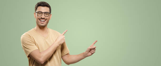 베이지 색 티셔츠와 안경을 입은 웃는 남자의 배너, 손으로 오른쪽에 상업적 제안을 보여줍니다. - human gender white green brown 뉴스 사진 이미지