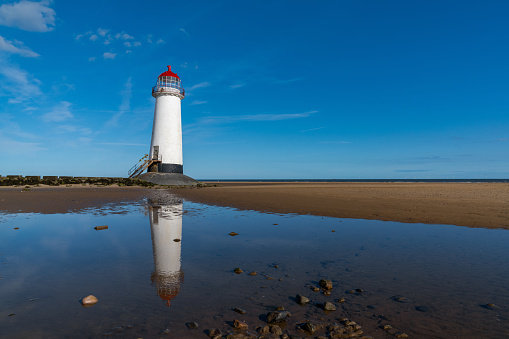 view of the Point of Ayr Lighthouse and Talacre Beach in northern Wales with reflections in a tidal pool
