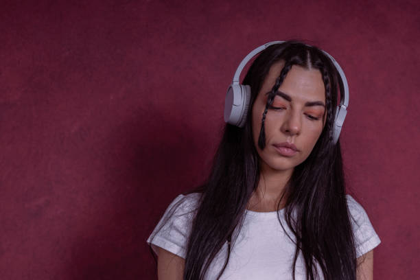 Sad young woman listening to music in headphones. She looks lonely, depressed, tired, has negative emotions. Mental health and stress management topic