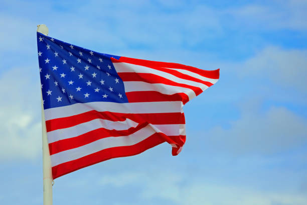 istock American Flag waving in the blue sky with some clouds 1433429688