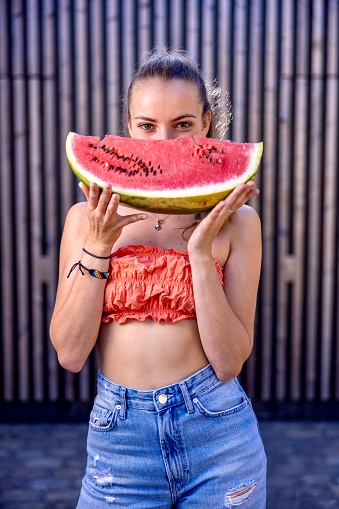 Attractive girl in summer clothes holding a watermelon