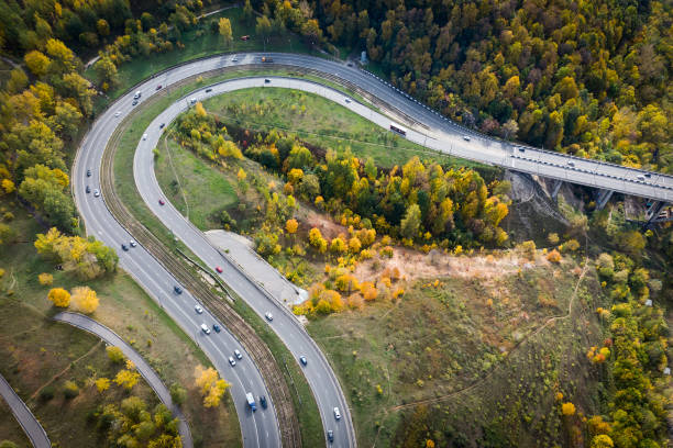 vista aérea de la carretera con un bosque de otoño y una ranura en la carretera. - road winding road mountain spiral staircase fotografías e imágenes de stock
