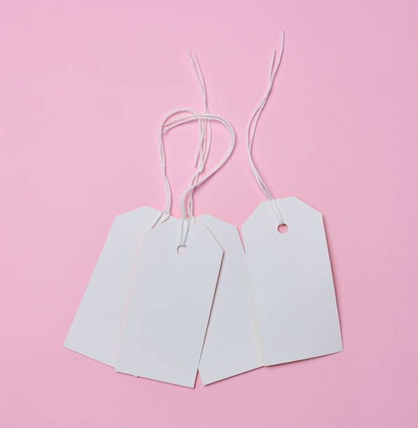 istock Empty white cardboard tag on a white rope, pink background. Price tag template 1433434845