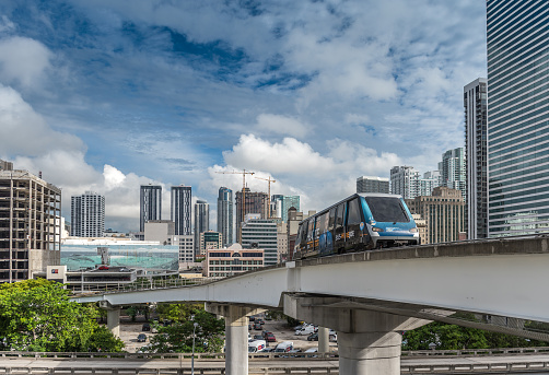 Miami, USA - October 14, 2022: View of Downtown Miami and public transportation system. The image shows the Metromover system, an electric car crossing the ramp over the Miami highway surrounding by modern skyscrapers. Metromover is a free mass transit automated people mover train system operated by Miami-Dade Transit in Miami.