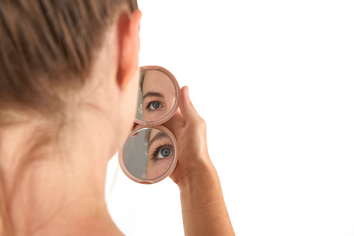 closeup views of beautiful blue eyes on double mirror at models hand