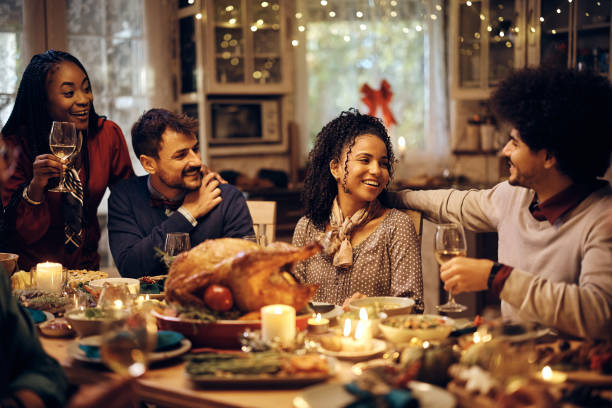 istock Happy friends enjoying in Thanksgiving dinner party at dining table. 1433453876
