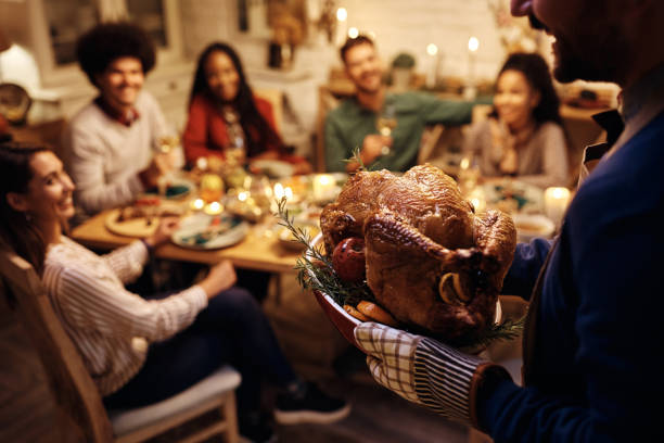 nahaufnahme eines mannes, der gebratenen truthahn während der thanksgiving-dinnerparty mit einem freund serviert. - thanksgiving stock-fotos und bilder