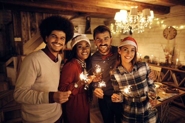 istock Young happy people using sparklers and drinking wine while celebrating New Year and looking at camera. 1433454075