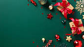 Green Christmas background with gift boxes with red ribbon bow, decorations, baubles. Merry Christmas and Happy New Year banner design, cover, postcard template.