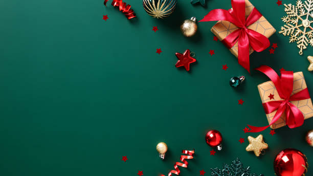 Green Christmas background with gift boxes with red ribbon bow, decorations, baubles. Merry Christmas and Happy New Year banner design, cover, postcard template. stock photo