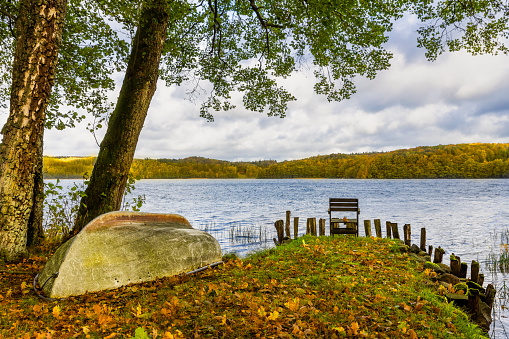 Autumn lake scenery with a boat and a chair at shore