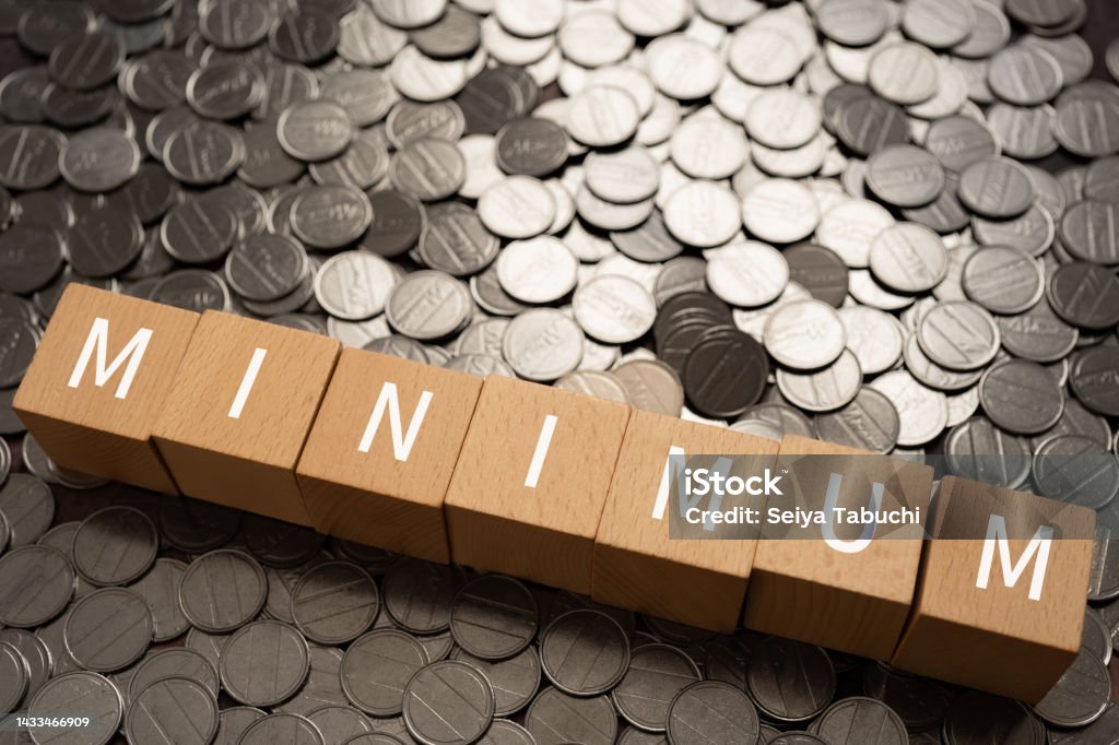 Wooden blocks with "MINIMUM" text of concept and coins. Wages Stock Photo