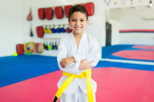 Happy latin boy smiling wearing a kimono and yellow belt at taekwondo training