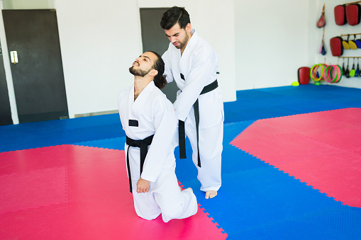Young men with black belts practicing karate and fighting during a taekwondo practice