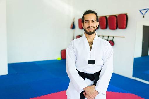 Handsome latin advanced student smiling while ready for a taekwondo practice