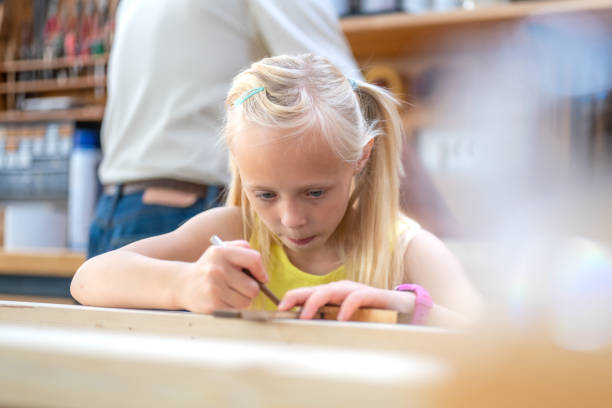 istock Concentrated little girl doing woodwork in craftsman workshop 1433471524