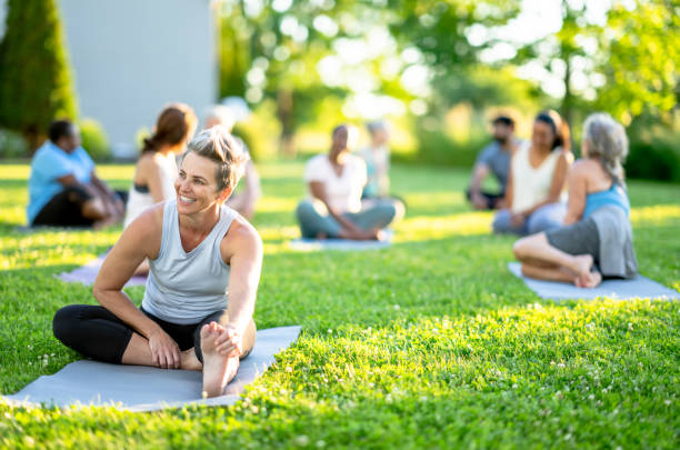 Adult outdoor yoga A diverse group of adults sit on their yoga mats and happily chat with each other. lgbtqcollection stock pictures, royalty-free photos & images