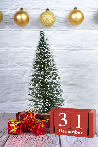Decorative Christmas tree, gift boxes and red wooden perpetual calendar with date on white wooden background. Banner, header, New Year background with copy space