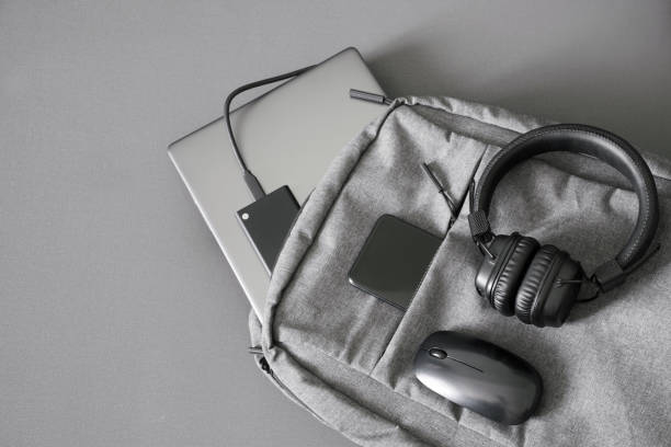 istock Small textile urban backpack with gray laptop, external SSD drive, smartphone, mouse and wireless headphones. Traveling with gadgets. College student backpack. Duoton. Shades of gray 1433473509