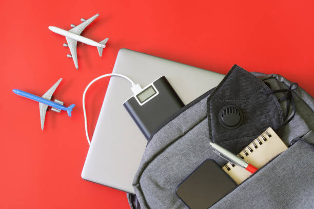 istock Backpack and laptop, external battery - power bank, mobile phone, notepad and protective mask. On red background next to toy airplanes. Concept of gadgets for air travel and relocation. 1433473519