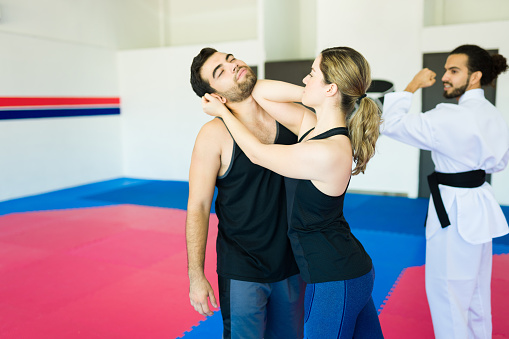 Adult woman at the martial arts school practicing self-defense training with a young man