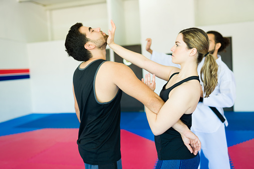 Attractive woman and young man fighting during a personal defense class