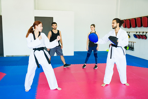 Karate coach and young woman with a black belt ready for a taekwondo practice