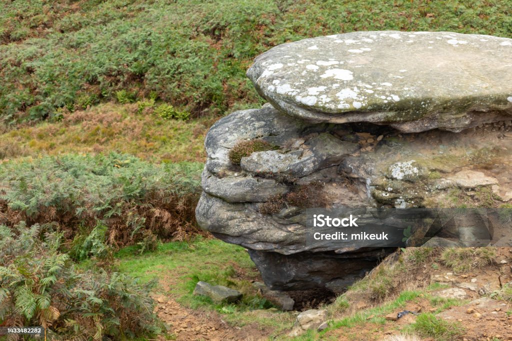 Sandstone weathered rock outcrop in Yorkshire England UK looking like an old man wearing a flat cap hat Ancient Stock Photo