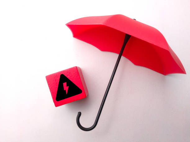 istock Red umbrella and red cube with an electrical hazard sign on white background. 1433483276