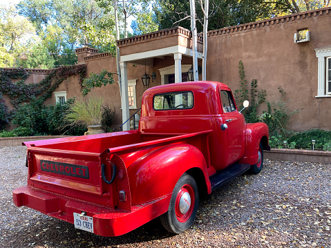 Santa Fe, NM: A vintage 1950s red pickup truck parked in front of an adobe house near downtown Santa Fe, NM.