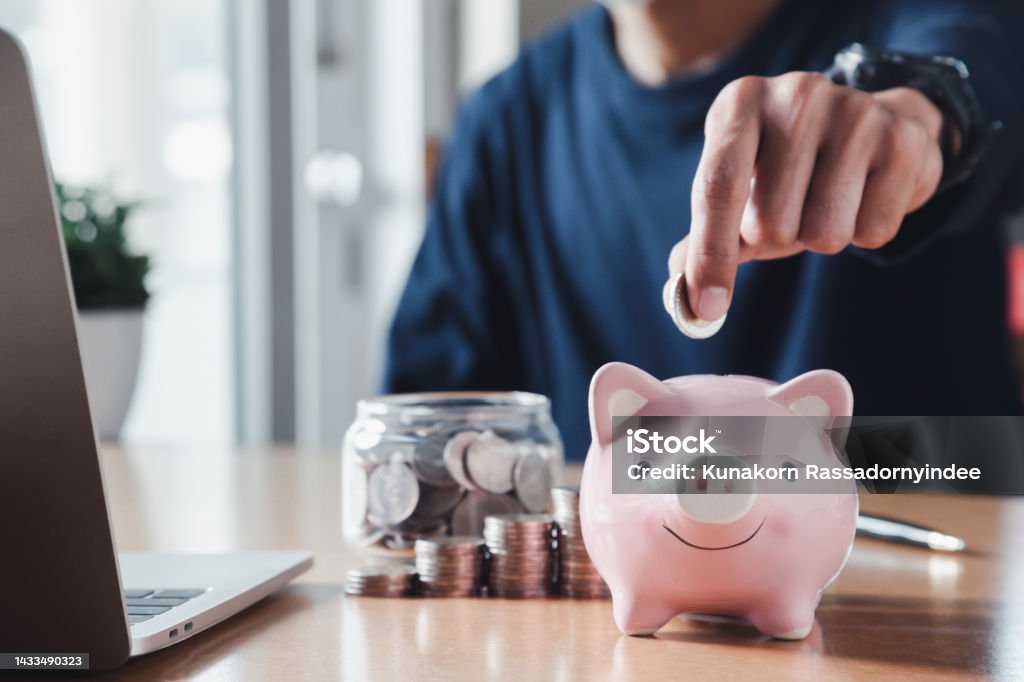 Hand putting coins in a piggy bank for save money and Saving Money concept. Savings Stock Photo
