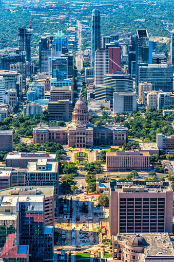 Aerial view of the iconic Texas State Capitol Building in the foreground with the skyline of beautiful Austin, Texas behind shot from an altitude of approximately 1000 feet over the city on a clear early autumn morning.