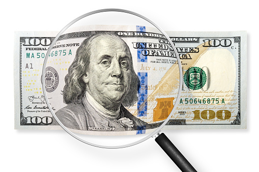 One hundred dollars note on a white background. View through magnifying glass