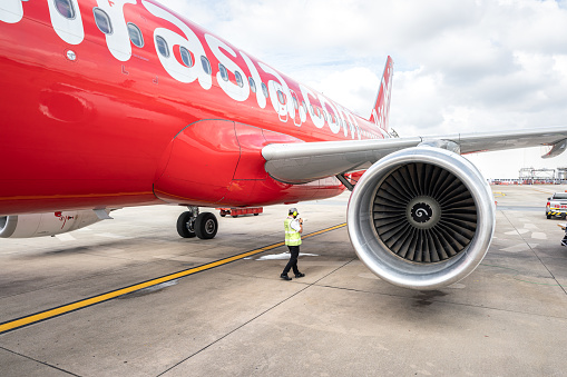 Thailand - October 2022 : A mechanical engineer is checking on the Airasia airplane the verify to condition before taking-off. People working in transportation industrial editorial photo.