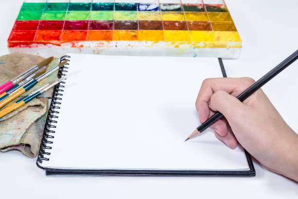 istock Human hand holding pencil with note book and tray colors 1433523296