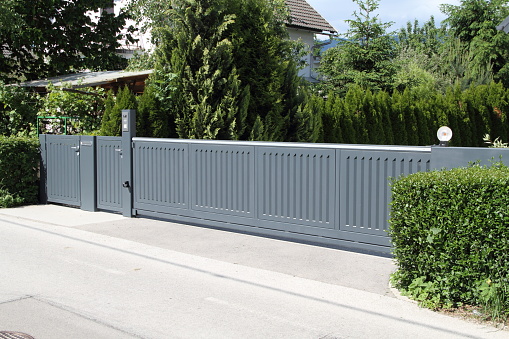 a driveway with a gray sliding gate in front of a beautiful house